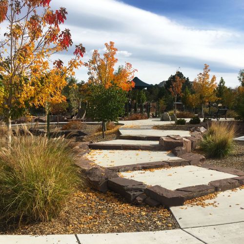     A well-developed concrete path leads to a bench area. Natural materials are incorporated into the construction to create unique experiences.