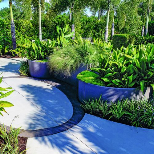 A small oval area is marked off, framed by a distinctive darker colored paving band that signals a change in sensory experience. It is surrounded by custom-designed planters that vary in height, bringing a variety of sensory-appropriate plants within easy access.