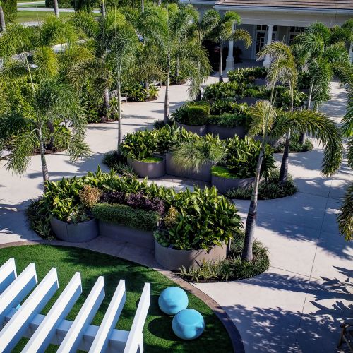 An overview of the garden from above the pergola. A spacious curved trellis serves as a welcoming transition from the elementary school to the garden. The adjacent activity space, an oval “lawn” of resilient paving, features a variety of fixed and movable seating choices.