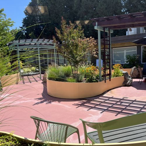 The garden has separate seating areas that allow privacy for groups who want space for themselves. The path curves around a planter divider built between the two private spaces, leading to a shaded area. 