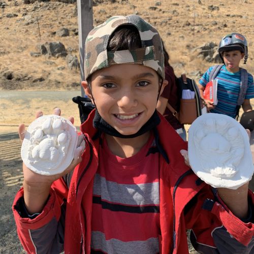 A young boy proudly shows off his animal track imprints during an activity where youths create animal tracks on clay.