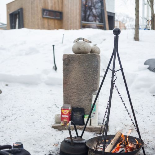 Snow covers the ground outside of the Outdoor Care Retreat. An outdoor fireplace is set up for people to keep warm during the winter chill. Photo credit: Øystein Horgmo