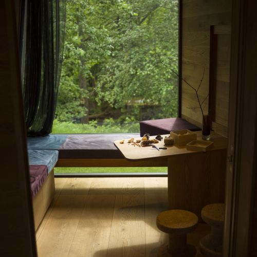 The inside of the interior therapy room. A large window stretches over a sitting area, revealing a clear view of the vibrant, green forest outside. Photo credit: Øystein Horgmo