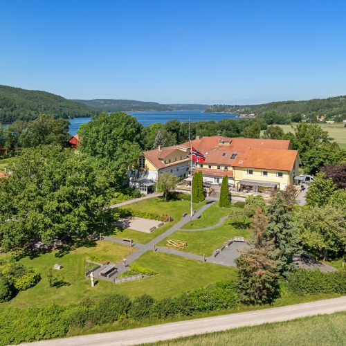 An aerial view of the garden, with the multi-story Unicare Bakke hospital in the background. Groves of mature, leafy trees flank the vertical axes of the rehabilitation garden.